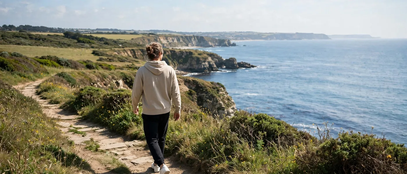 Person walking outdoors on a coastal path in bright daylight